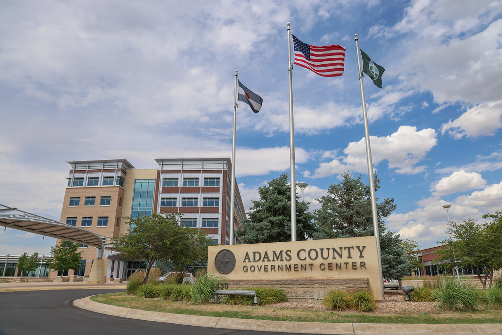 Adams County Government Center entrance with flagpoles and modern building in background