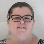 Person with glasses and headband, smiling, against plain background.