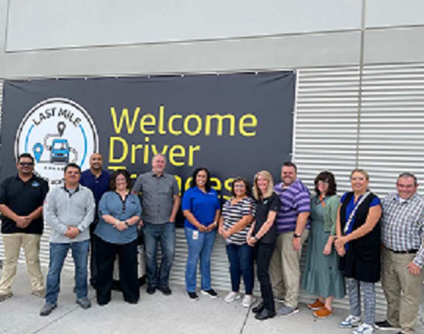 Group standing in front of 'Welcome Driver Associates' banner at Last Mile location.