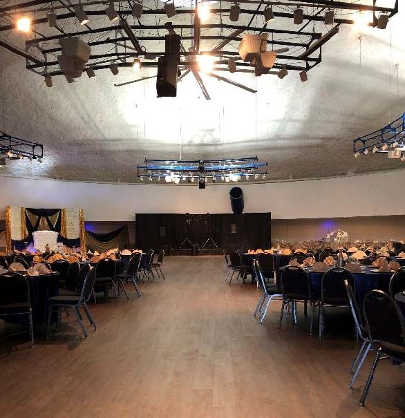 Spacious event hall with tables set for a formal gathering.