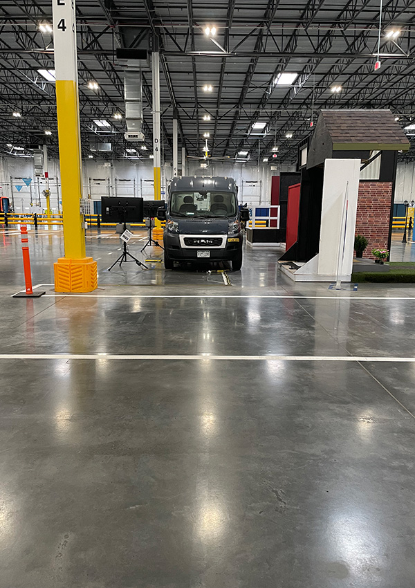 Van parked inside warehouse with tripods and testing setup nearby