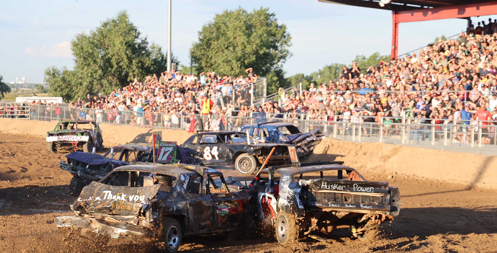 Demolition derby with cars colliding in front of a large crowd