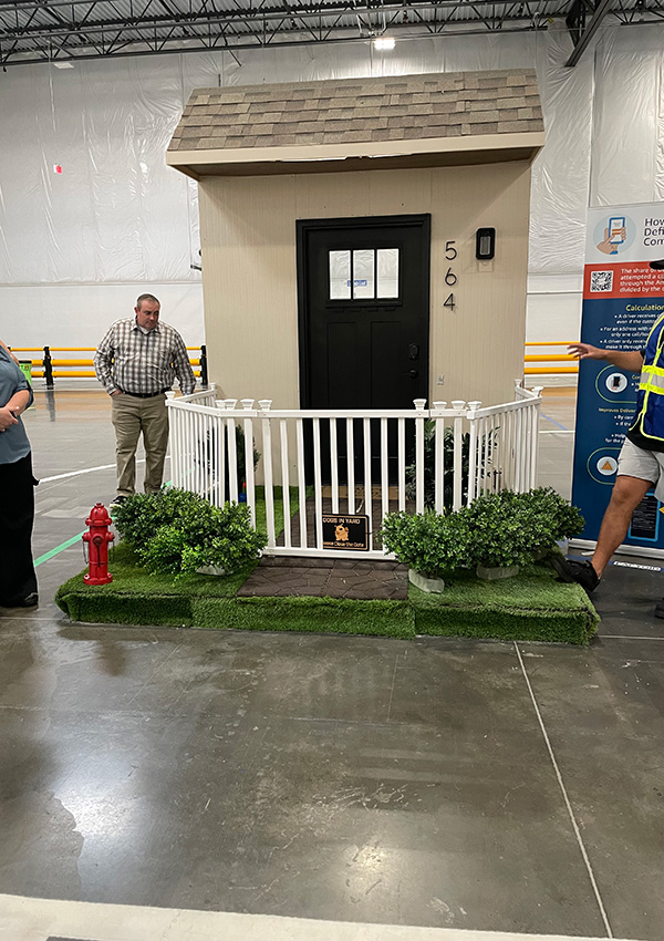 Small house display with white fence, red fire hydrant, and numbered door 564.