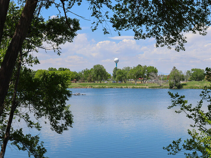 Calm lake surrounded by trees with water tower in background.