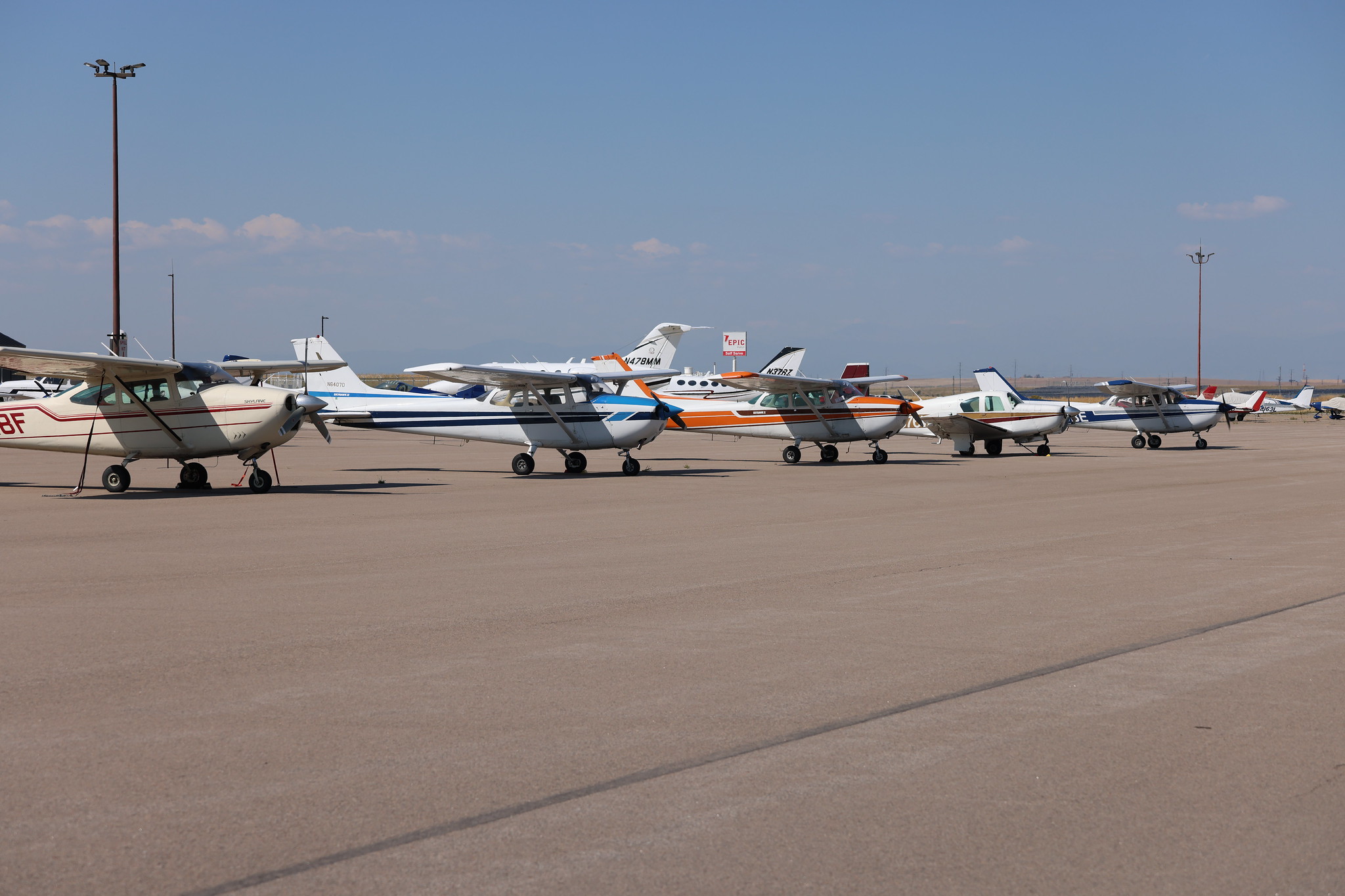 Small aircraft lined up on an airport runway on a clear day.
