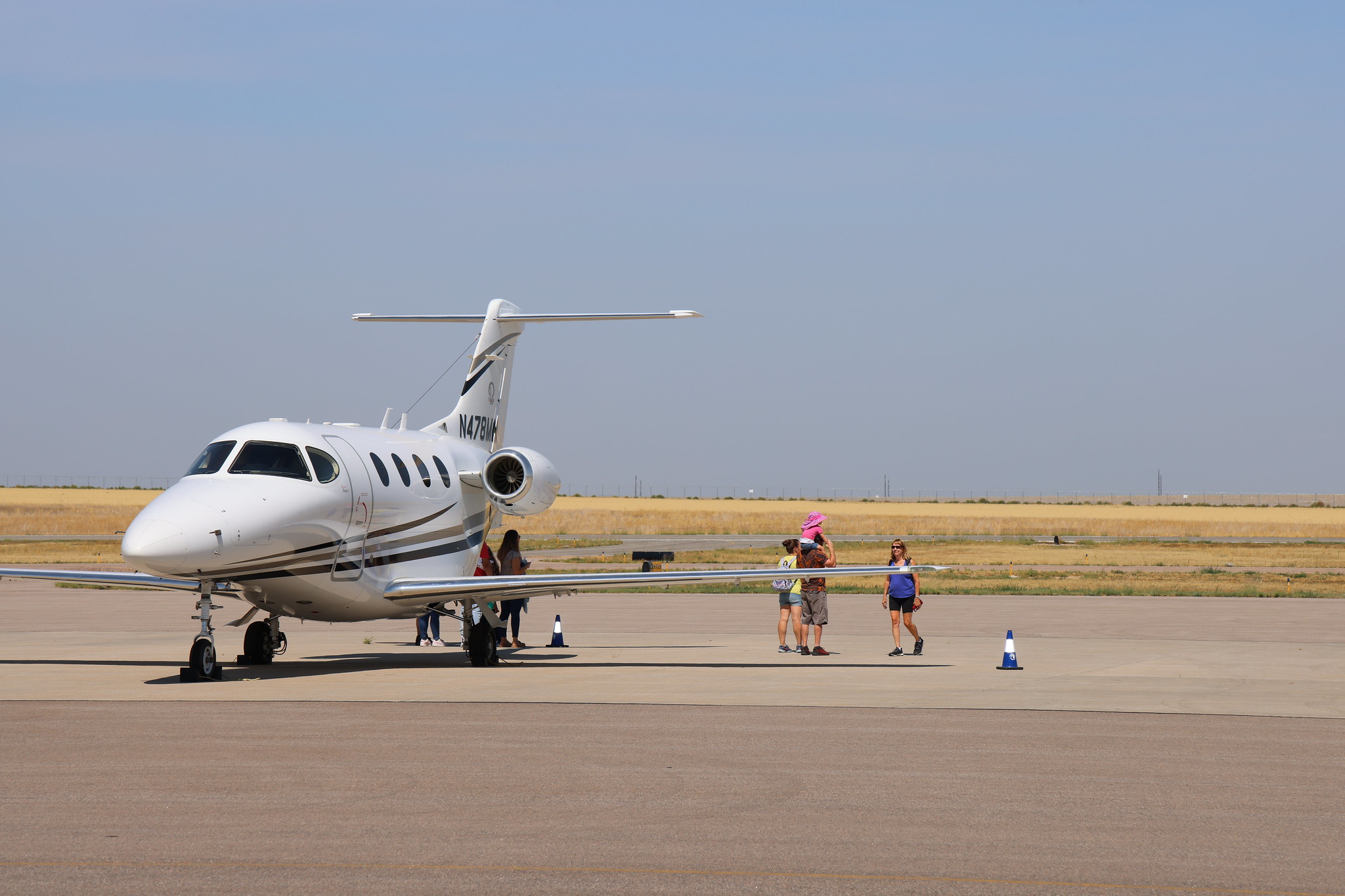 White private jet on tarmac with N478MA written, people nearby.