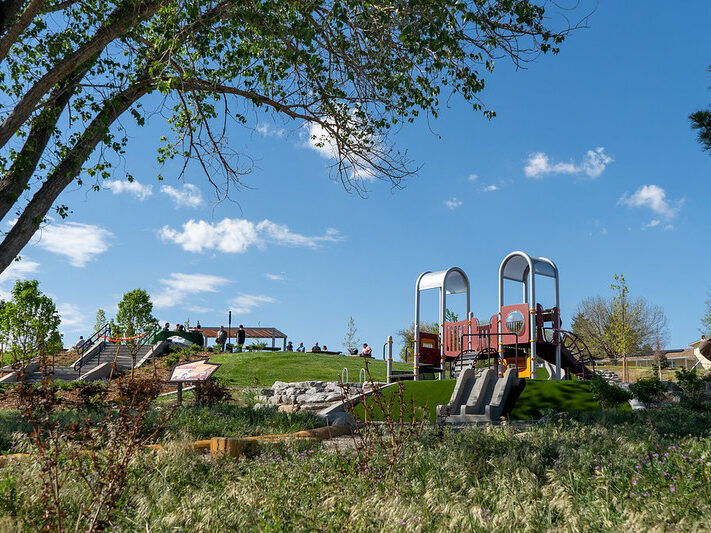 Playground with slides and climbing structures under a clear blue sky.