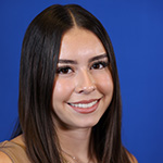 Adriyanna Ramirez smiling against a solid blue background.