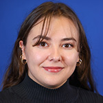 Bianca Estrada smiling against blue background, wearing a black top.