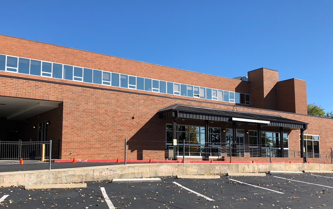 Brick building with large windows and an awning over the entrance.