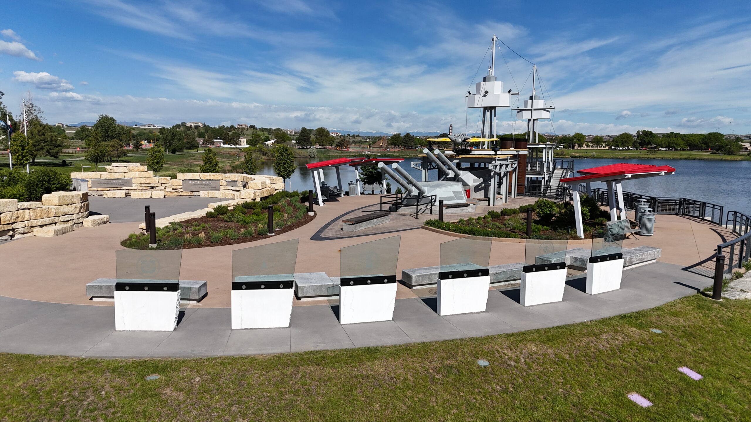 Outdoor museum display with large canons, red-roof structures, and scenic lake view