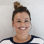 Diana smiling warmly, hair in a bun, wearing a striped sweater