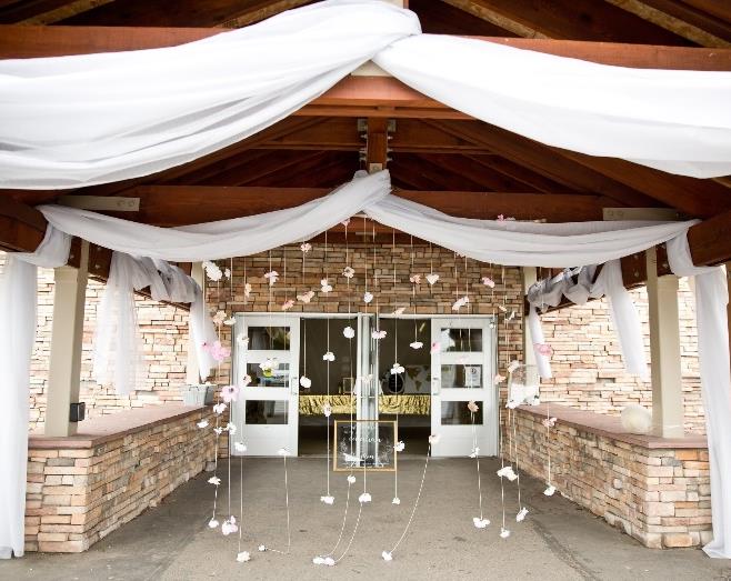 Celebration venue entrance decorated with white drapes and hanging flowers.