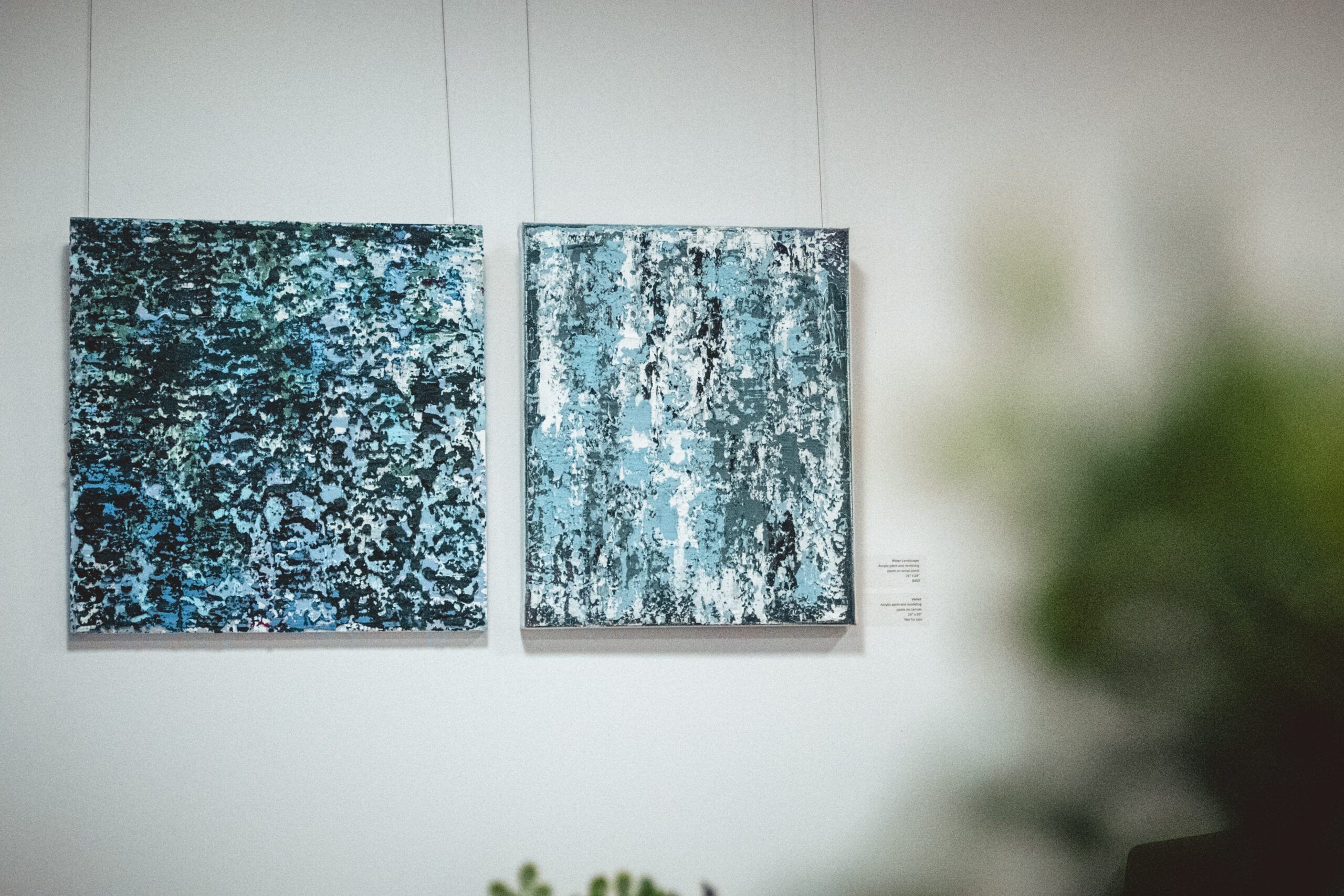 Two abstract paintings with blue and white textures hanging on a wall