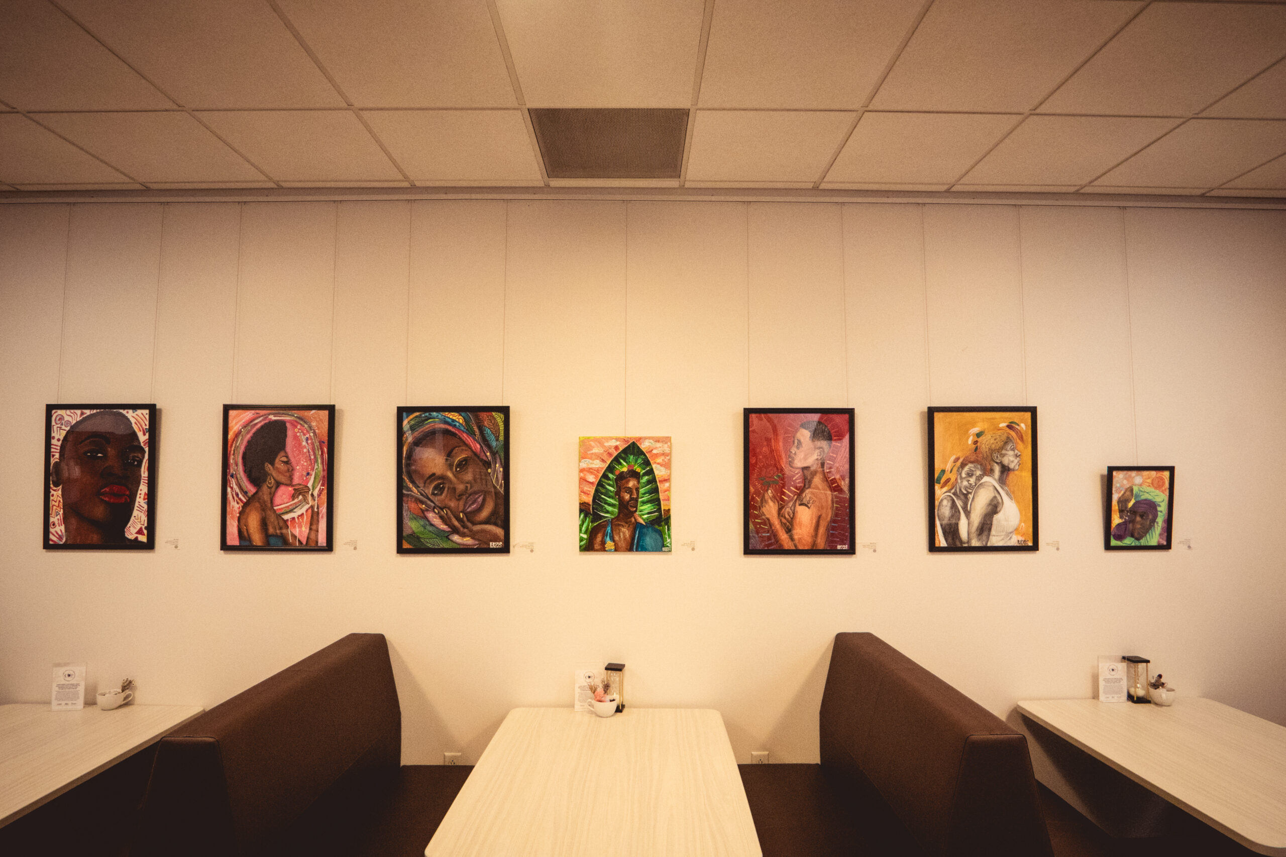 Art gallery wall displaying vibrant portraits above two cafe-style booths