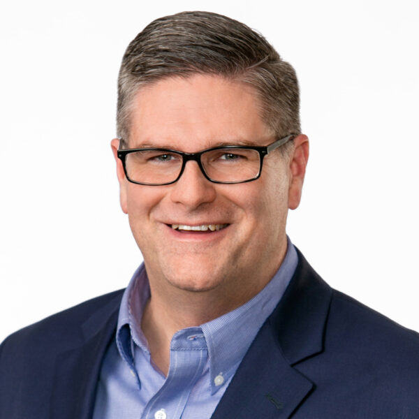Fanning smiling, wearing glasses and blue suit with a light blue shirt