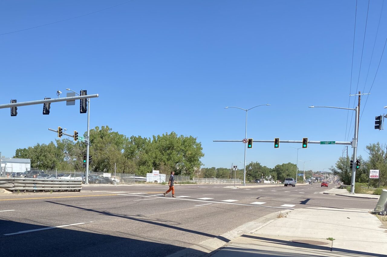 A person crosses a wide street at a traffic light on Clear Creek with "King's Auto Sales" sign visible nearby.
