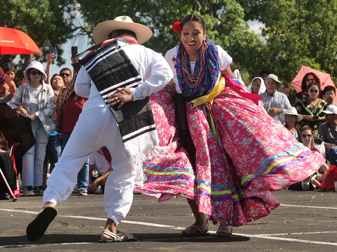 Dancers in colorful traditional attire performing at Festival Latino, surrounded by an attentive crowd.
