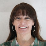 Gabriella Sanchez smiling, wearing hoop earrings and a plaid shirt