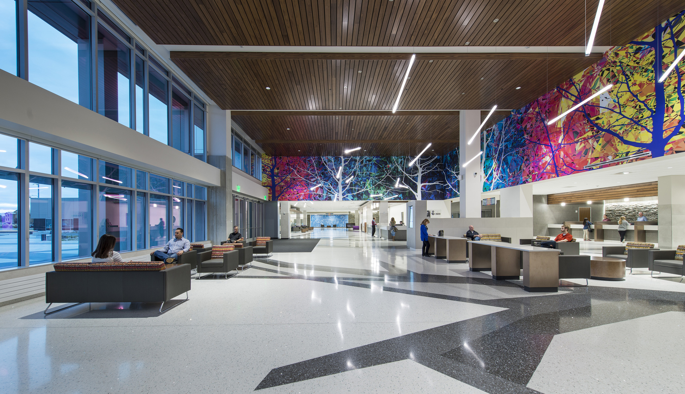 Spacious modern lobby with colorful wall art, seating areas, and people interacting.