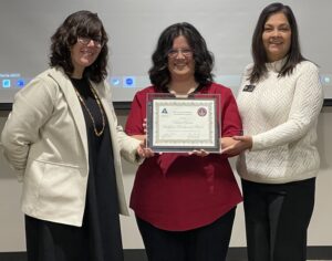 Three smiling people; center holds a framed Colorado workforce board certificate.
