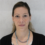 Judith Caldera smiling, wearing a necklace and black cardigan against a neutral background