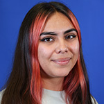 Kennia smiles against a solid blue background, hair highlighted pink.