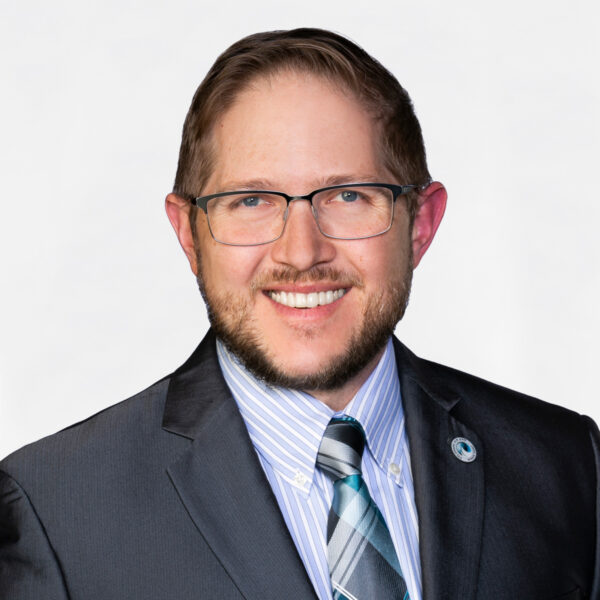 Kloska smiling in a suit with glasses and striped tie