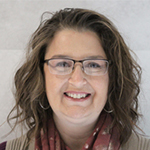 Linda smiling with short, wavy hair and glasses