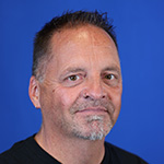 Marc-Bullion smiling slightly against blue background.