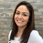 Maritza Espinoza smiling in front of a textured stone wall