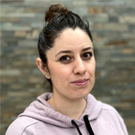 Martha Guerrero smiling in a hoodie against a stone wall background