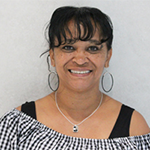NajlaNajee-Ulla smiling, wearing a checkered top and hoop earrings.