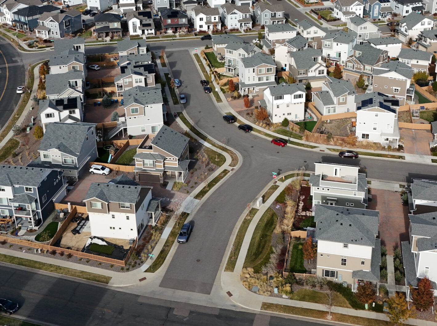 Aerial view of a neighborhood with modern houses, curved streets, and green spaces.