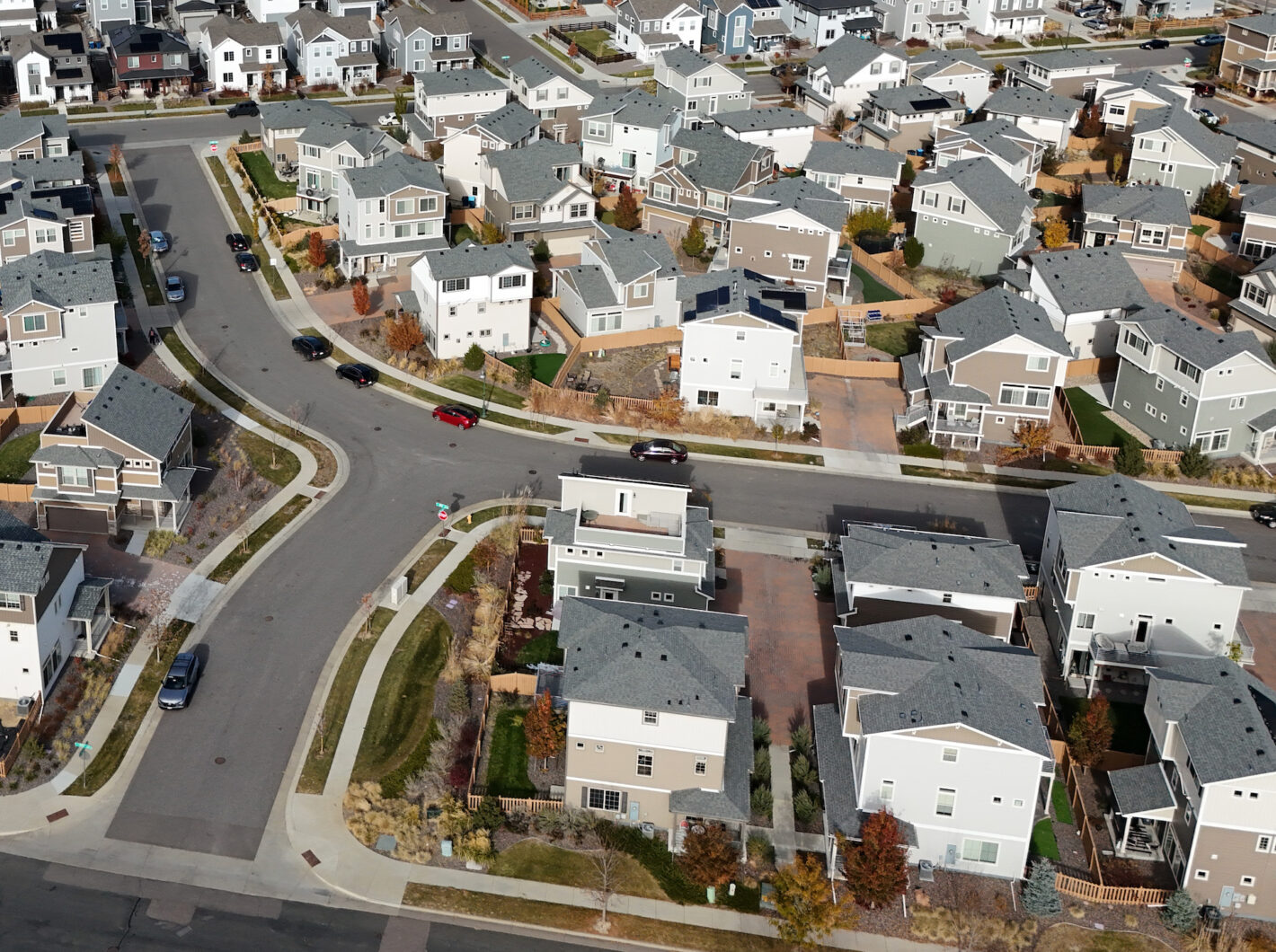 Aerial view of a neighborhood with modern houses, curved streets, and green spaces.