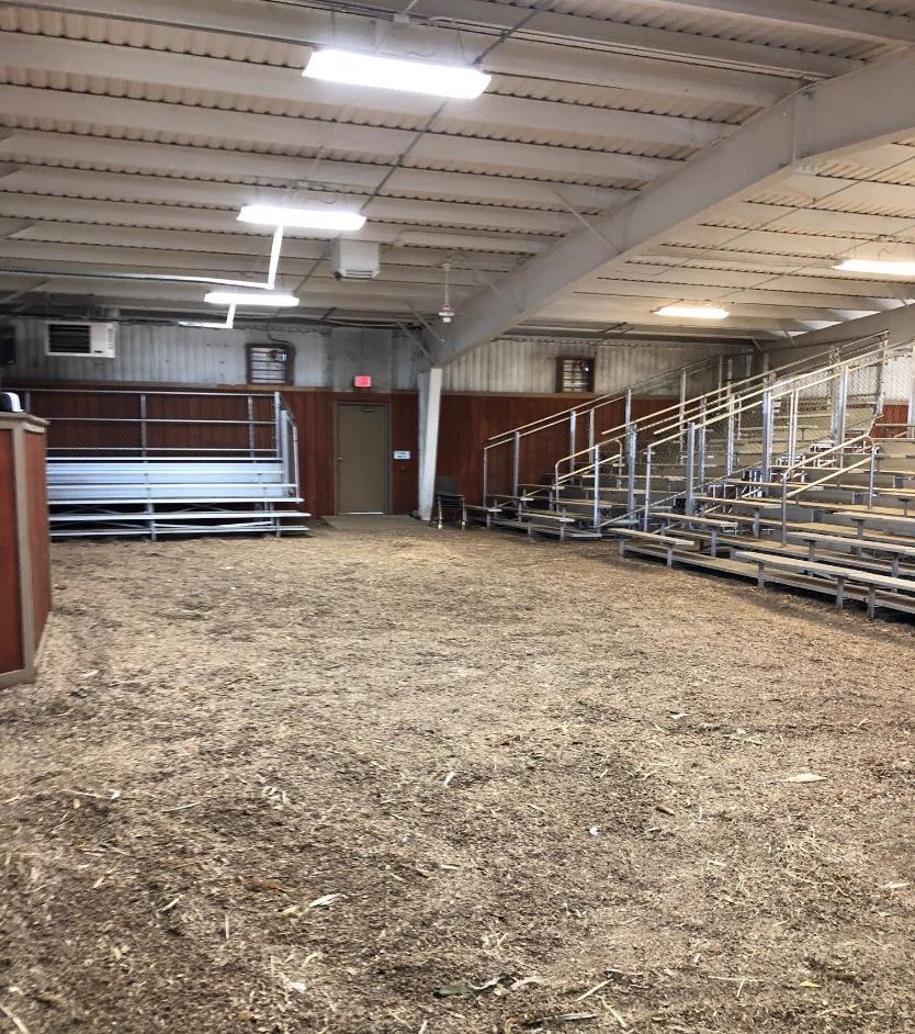 Interior of a barn with bleachers and dirt-covered floor.