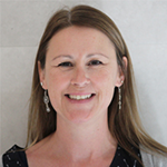 Wendy smiling against a neutral background, wearing a dark patterned top.