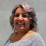 Yadira Barron smiling, wearing a gray patterned top against a neutral background