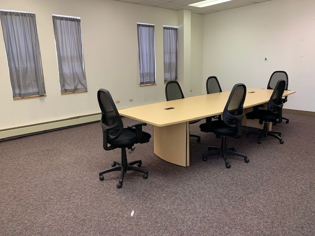Empty conference room with long table and six black chairs