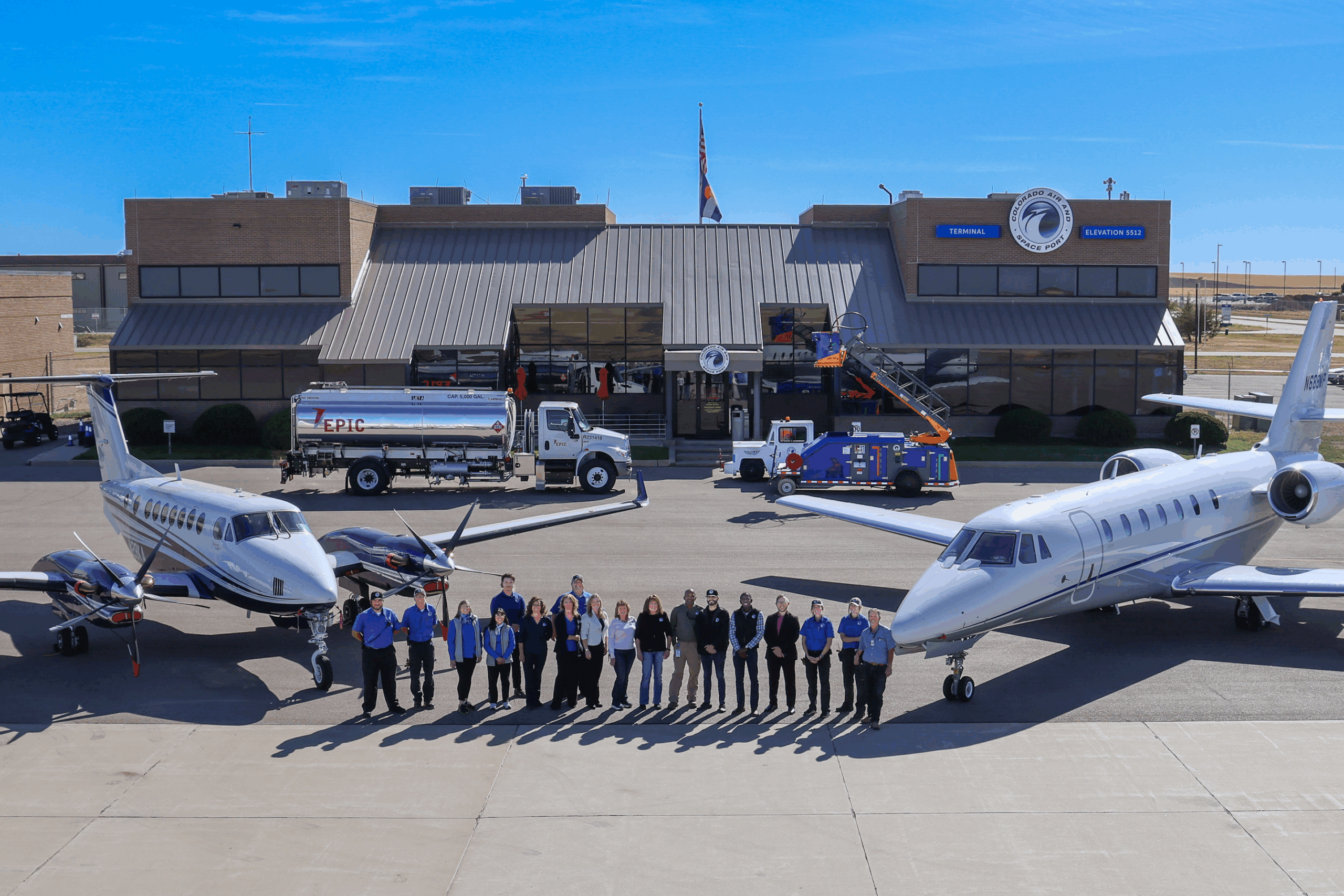 Group of people in front of two planes, airport terminal in background