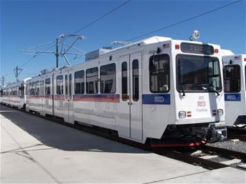 White RTD light rail train on sunny day at station.