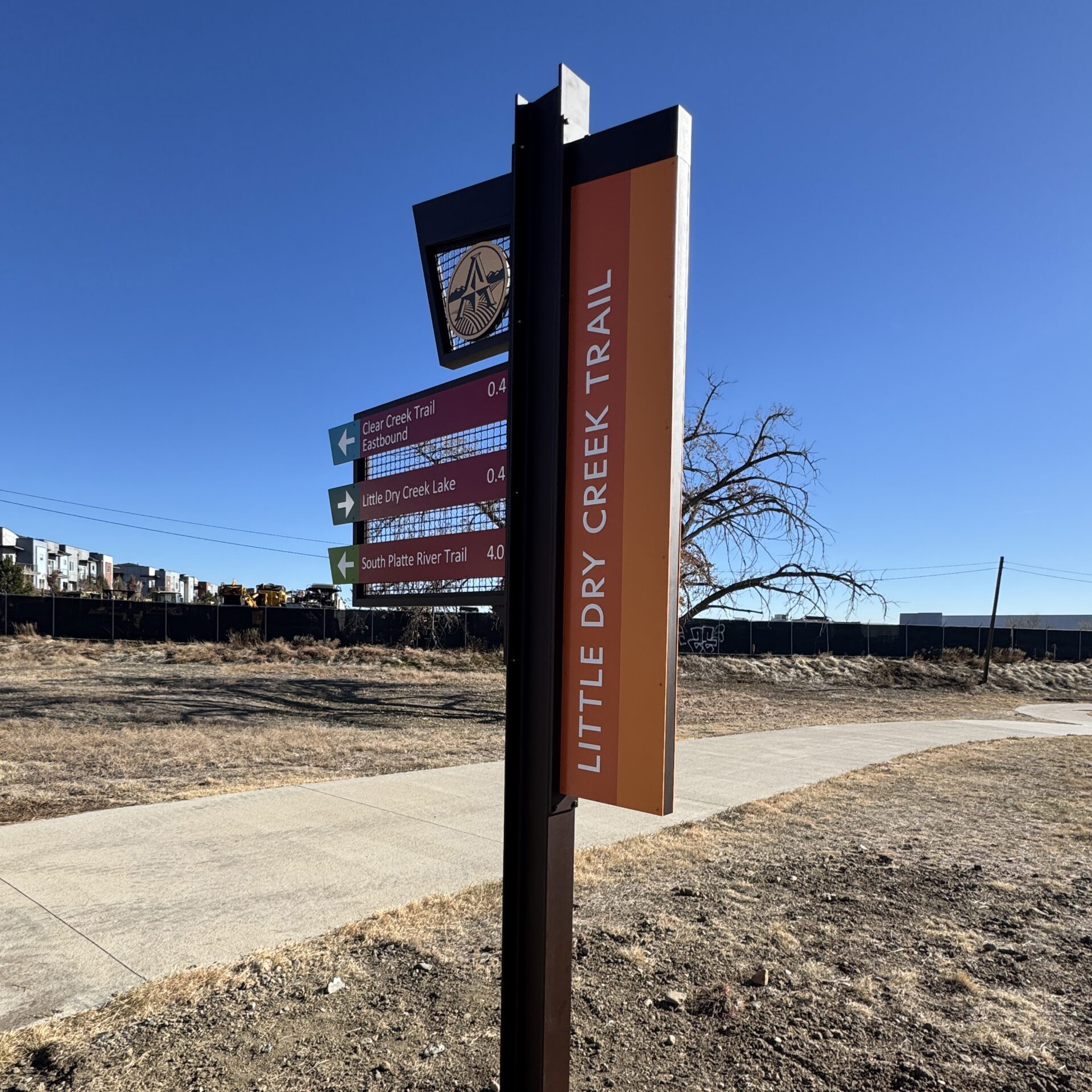 Trail sign with directions: "Clear Creek Trail Eastbound 0.4," "Little Dry Creek Lake 0.4," "South Platte River Trail 4.0"
