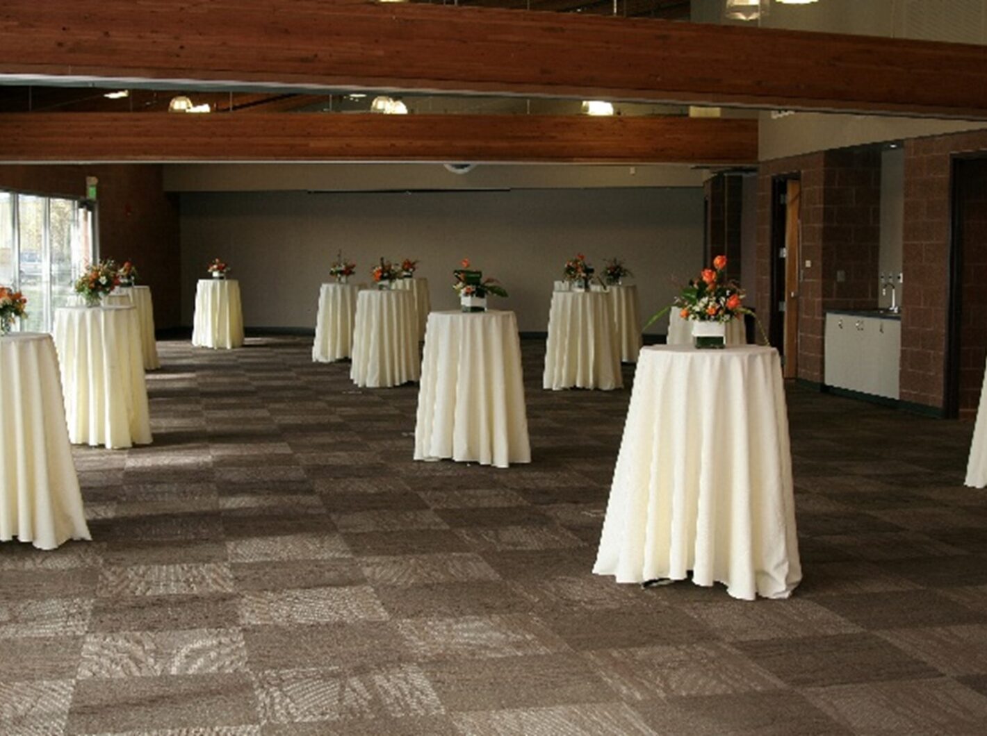 Banquet hall with spaced round tables, white tablecloths, and floral centerpieces.