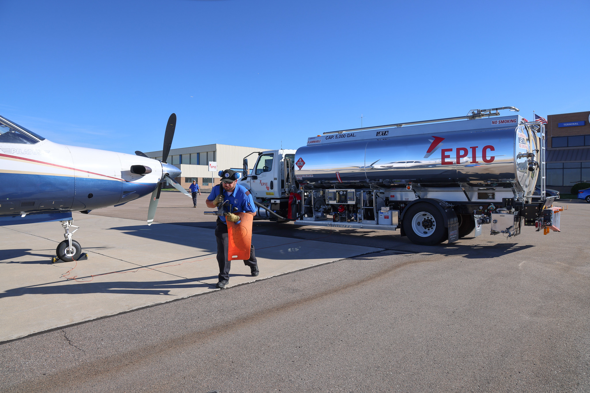 Worker prepares to refuel airplane with EPIC fuel tanker on tarmac.