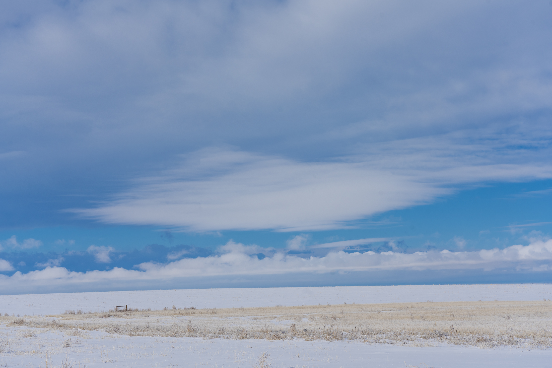 Snow-covered landscape with vast blue sky and scattered clouds