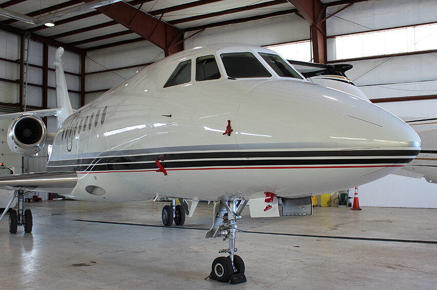 Private jet parked in a hangar featuring sleek white and grey design.