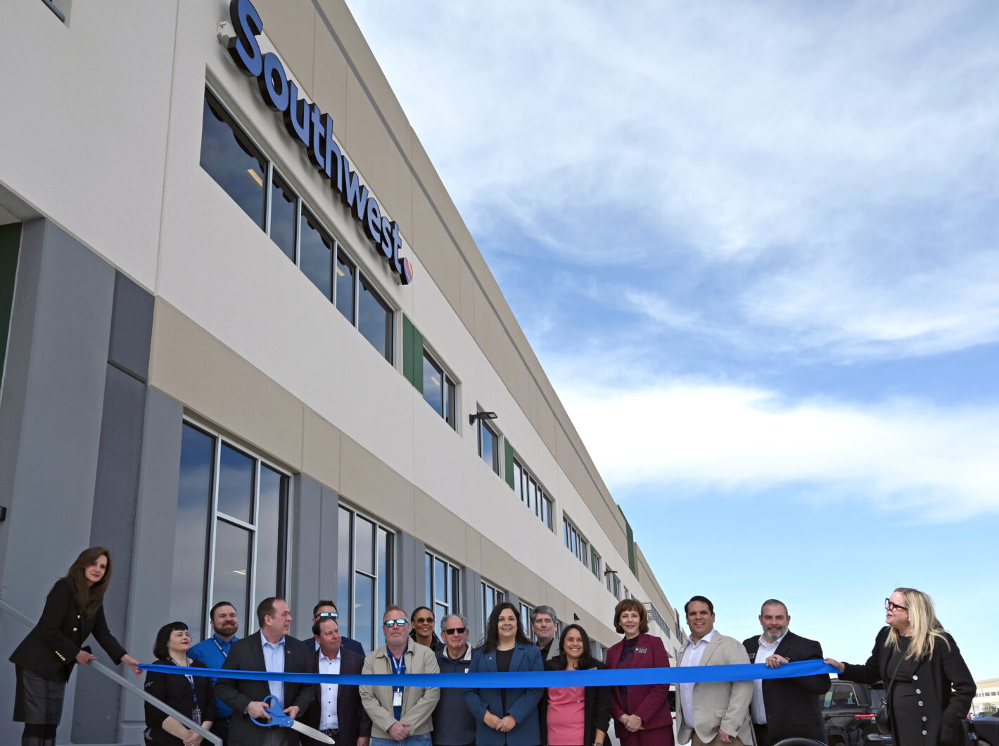 People gathered for a ribbon-cutting event outside a building with "Southwest" logo.