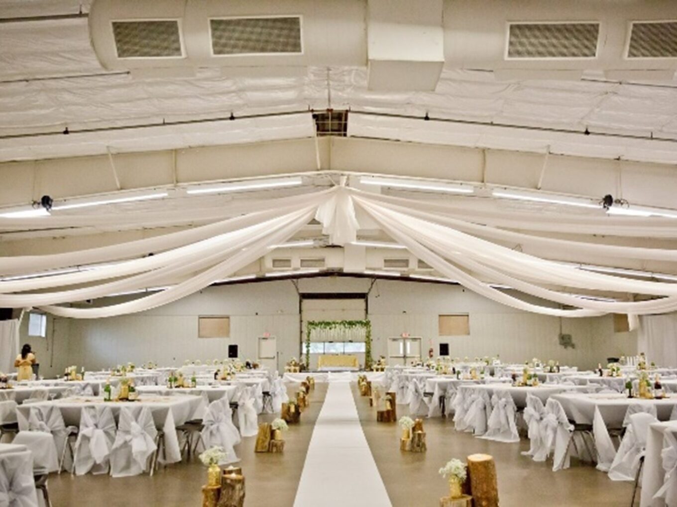 Wedding hall with white draped ceiling, aisle, and decorated tables