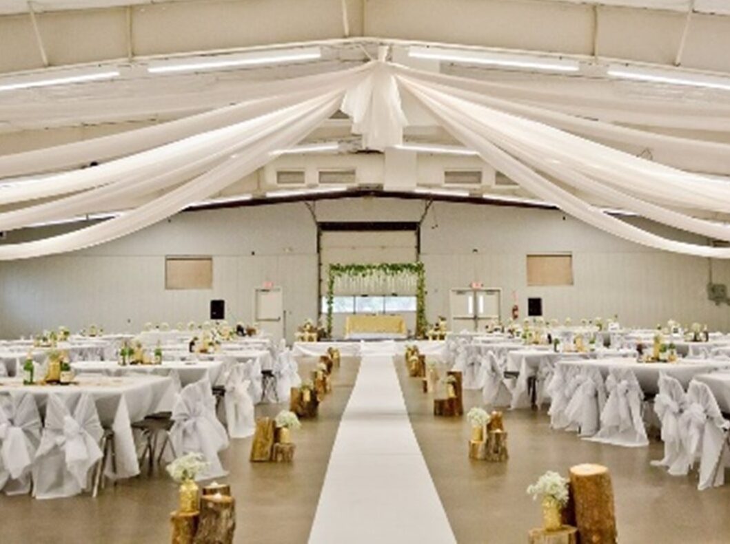 Wedding hall with white draped ceiling, aisle, and decorated tables