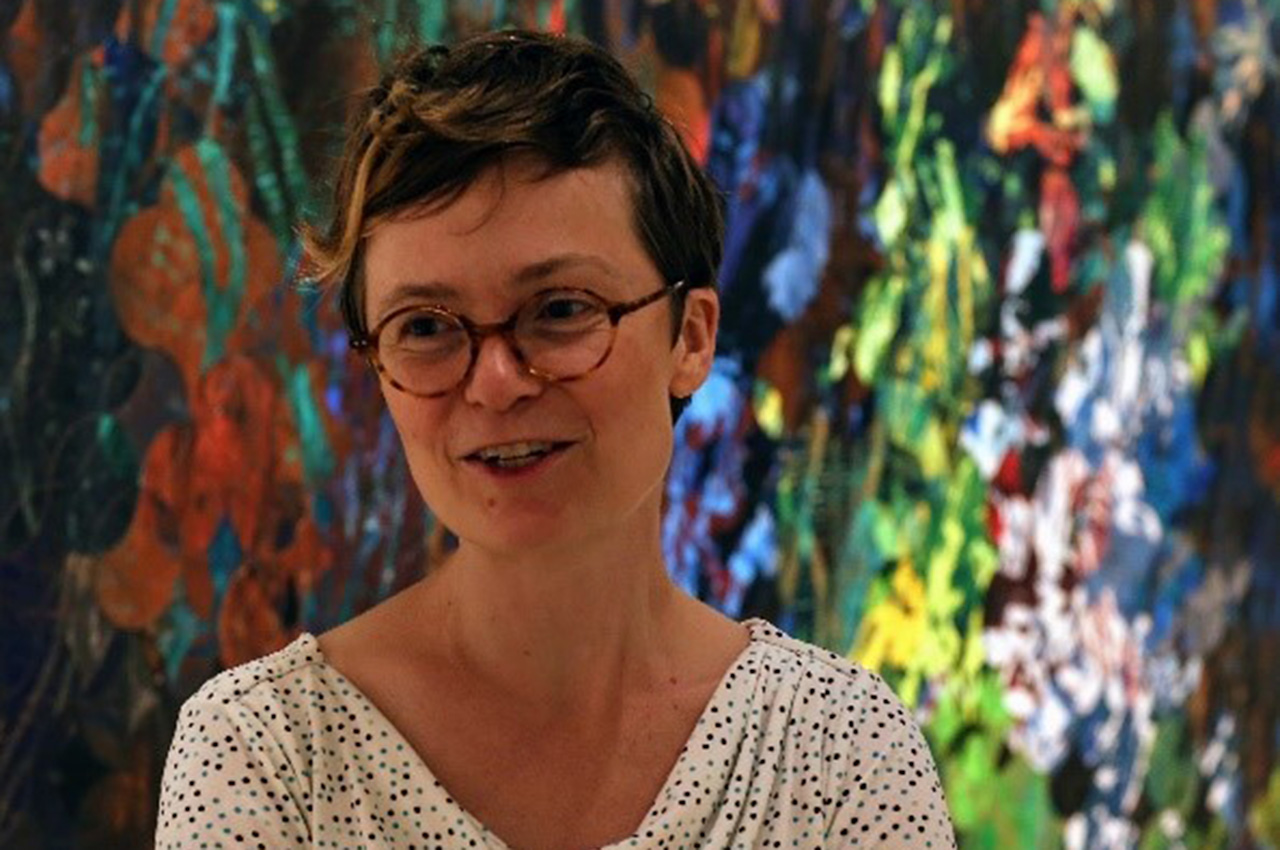 Holly smiling in front of colorful abstract painting.